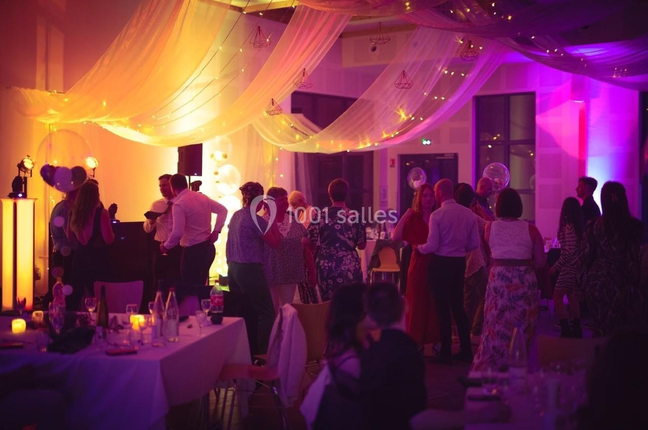 Groupe de personnes discutant et dansant dans une salle décorée de voilages et lumières tamisées.