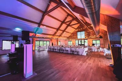 Salle de réception élégante avec tables rondes dressées, décorations florales et lumière naturelle entrant par les fenêtres.