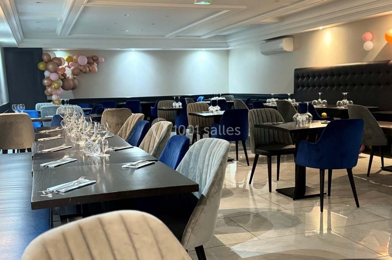 Salle de restaurant élégante avec tables dressées, chaises rembourrées et décoration murale de ballons colorés.