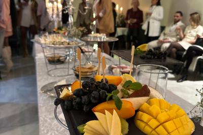 Plateau de fruits frais avec mangue, pomme, raisin et menthe, présenté sur une table lors d'un événement convivial.