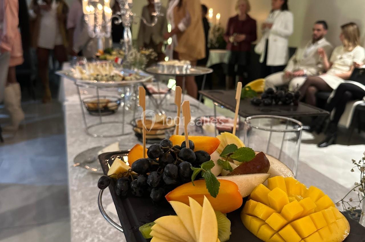 Plateau de fruits frais avec mangue, pomme, raisin et menthe, présenté sur une table lors d'un événement convivial.