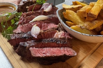 Assiette de pâtes garnie d'herbes fraîches servie avec des frites dans un restaurant à l'ambiance tamisée.