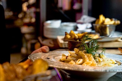 Assiette de pâtes garnie d'herbes fraîches servie avec des frites dans un restaurant à l'ambiance tamisée.