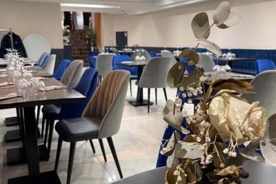 Salle de restaurant élégante avec tables dressées, chaises rembourrées et décoration florale en premier plan.