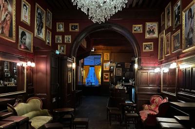 Miniature Location salle Lyon (Rhône) - L'Idole des Jeunes #13 Intérieur d'un bar avec un lustre central, des murs ornés de cadres et un comptoir en bois sombre.