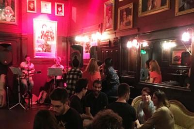 Miniature Location salle Lyon (Rhône) - L'Idole des Jeunes #2 Intérieur d'un bar avec un lustre central, des murs ornés de cadres et un comptoir en bois sombre.