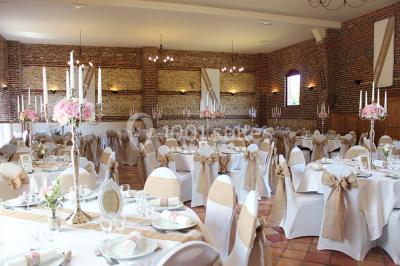 Salle de réception en briques avec éclairage chaleureux, grande table décorée de fleurs et vaisselle élégante.