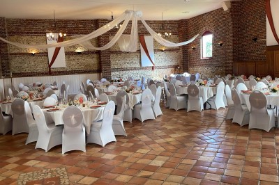 Salle de réception en briques avec éclairage chaleureux, grande table décorée de fleurs et vaisselle élégante.