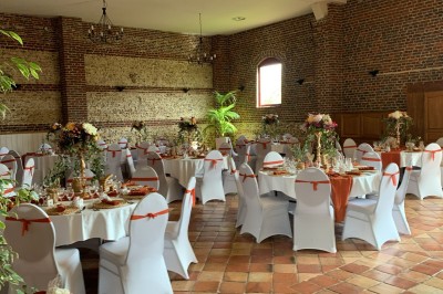 Salle de réception en briques avec éclairage chaleureux, grande table décorée de fleurs et vaisselle élégante.