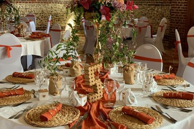 Salle de réception en briques avec éclairage chaleureux, grande table décorée de fleurs et vaisselle élégante.