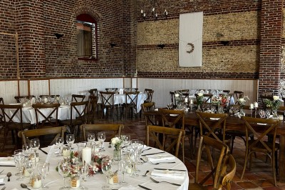 Salle de réception en briques avec éclairage chaleureux, grande table décorée de fleurs et vaisselle élégante.