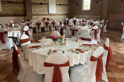 Salle de réception en briques avec éclairage chaleureux, grande table décorée de fleurs et vaisselle élégante.