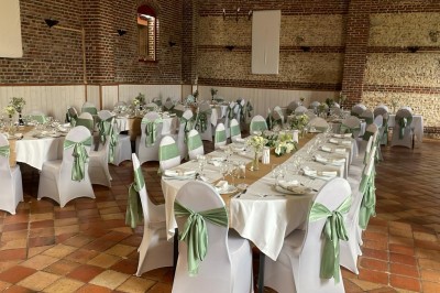 Salle de réception en briques avec éclairage chaleureux, grande table décorée de fleurs et vaisselle élégante.