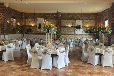 Salle de réception en briques avec éclairage chaleureux, grande table décorée de fleurs et vaisselle élégante.