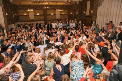 Salle de réception en briques avec éclairage chaleureux, grande table décorée de fleurs et vaisselle élégante.