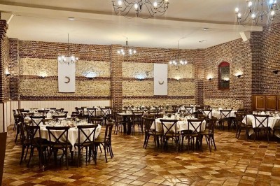 Salle de réception en briques avec éclairage chaleureux, grande table décorée de fleurs et vaisselle élégante.