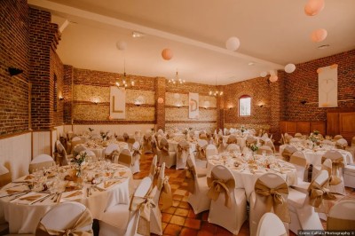 Salle de réception en briques avec éclairage chaleureux, grande table décorée de fleurs et vaisselle élégante.