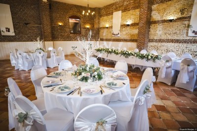 Salle de réception en briques avec éclairage chaleureux, grande table décorée de fleurs et vaisselle élégante.