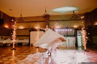 Salle de réception en briques avec éclairage chaleureux, grande table décorée de fleurs et vaisselle élégante.