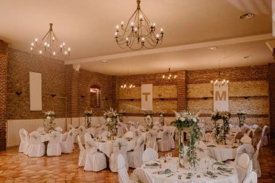 Salle de réception en briques avec éclairage chaleureux, grande table décorée de fleurs et vaisselle élégante.