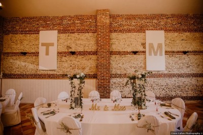 Salle de réception en briques avec éclairage chaleureux, grande table décorée de fleurs et vaisselle élégante.