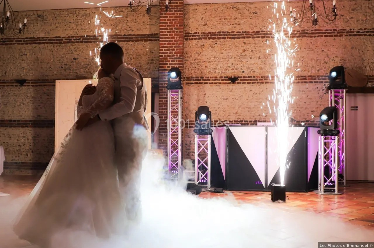 Un couple danse dans une salle décorée, entouré de fumée et d'effets pyrotechniques.