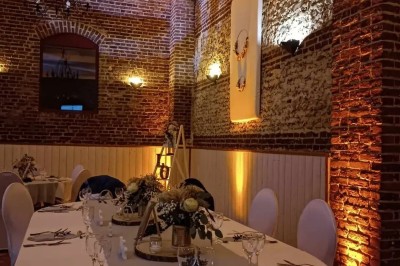 Salle de réception en briques avec éclairage chaleureux, grande table décorée de fleurs et vaisselle élégante.