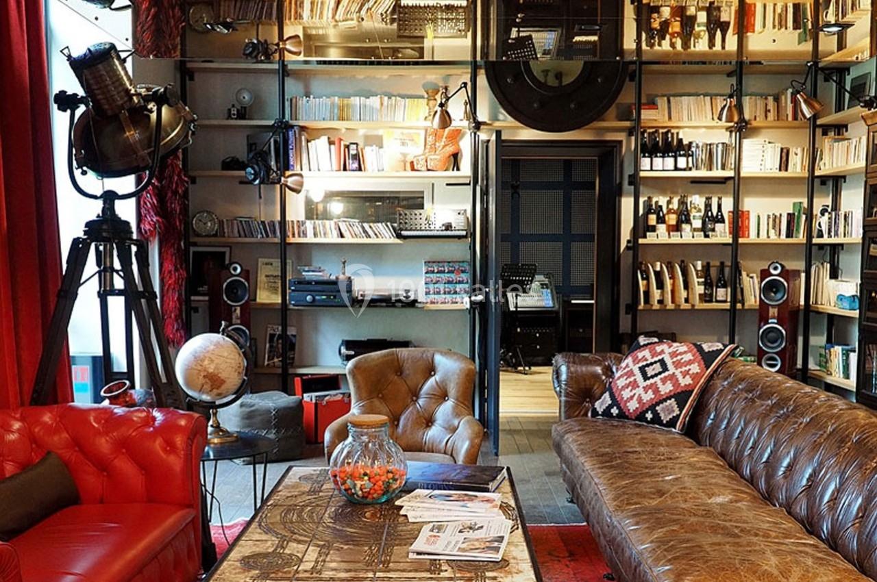 Salon chaleureux avec canapé en cuir, étagères remplies de livres, projecteur vintage et table basse décorée.