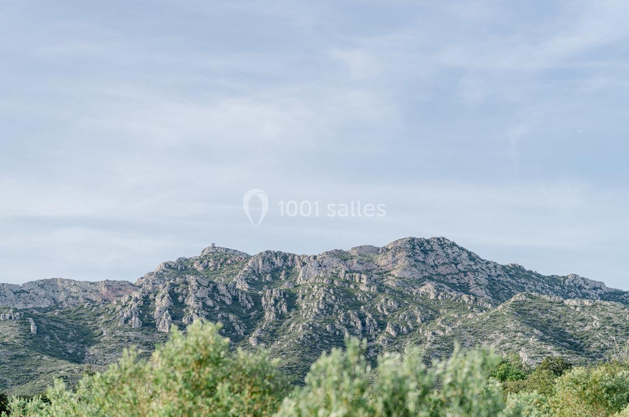 Paysage de montagnes rocheuses sous un ciel bleu clair, avec des arbres au premier plan.