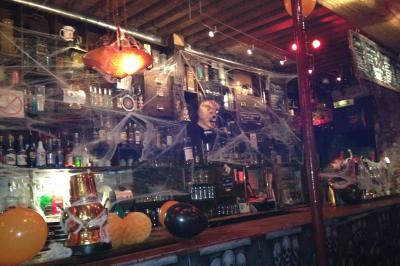 Intérieur d'un bar avec comptoir en bois, tabourets hauts, murs en pierre et éclairage tamisé.