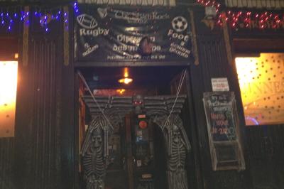 Intérieur d'un bar avec comptoir en bois, tabourets hauts, murs en pierre et éclairage tamisé.