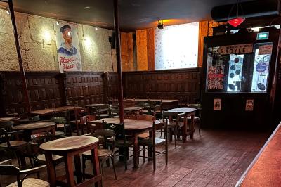 Intérieur d'un bar avec comptoir en bois, tabourets hauts, murs en pierre et éclairage tamisé.