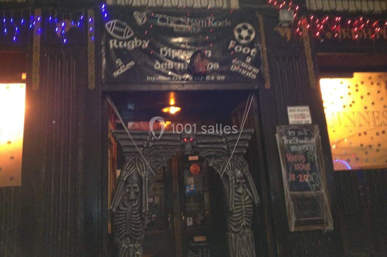 Entrée d'un bar décoré avec des squelettes et des lumières, avec une bannière annonçant des événements sportifs.