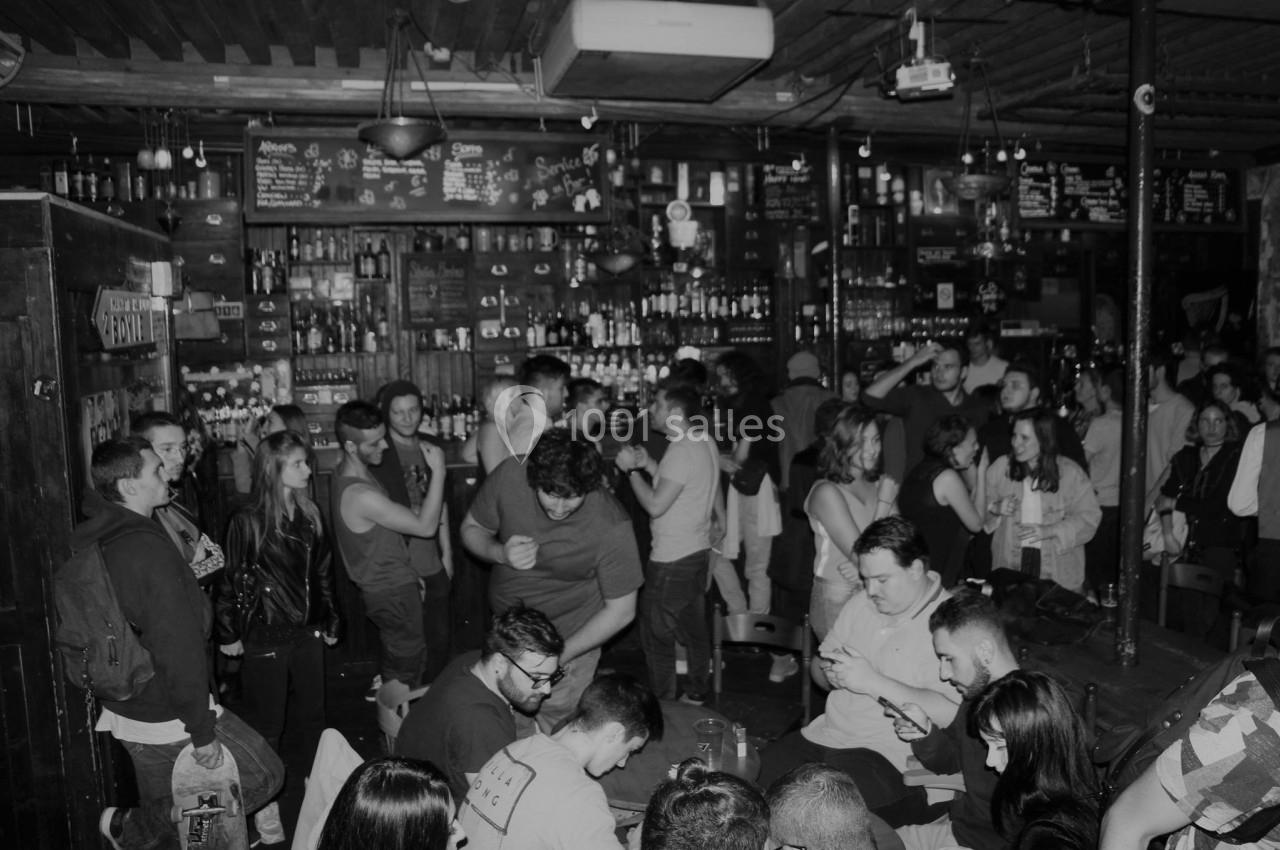 Groupe de personnes dans un bar animé, discutant et partageant un moment convivial dans une ambiance chaleureuse.