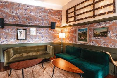 Terrasse de café avec tables et chaises alignées sur un trottoir, bordée de plantes et devantures de magasins.