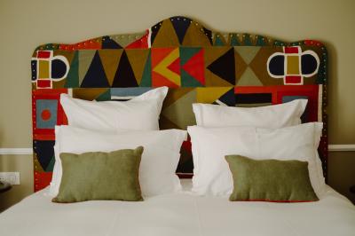 Fauteuil beige placé près d'un mur vert, avec un tableau encadré et des rideaux beiges en arrière-plan.