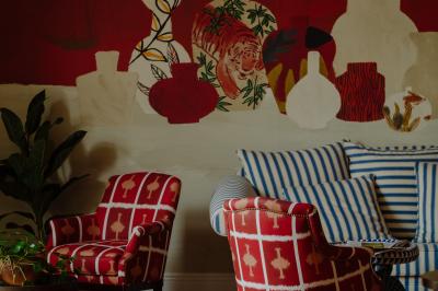 Fauteuil beige placé près d'un mur vert, avec un tableau encadré et des rideaux beiges en arrière-plan.