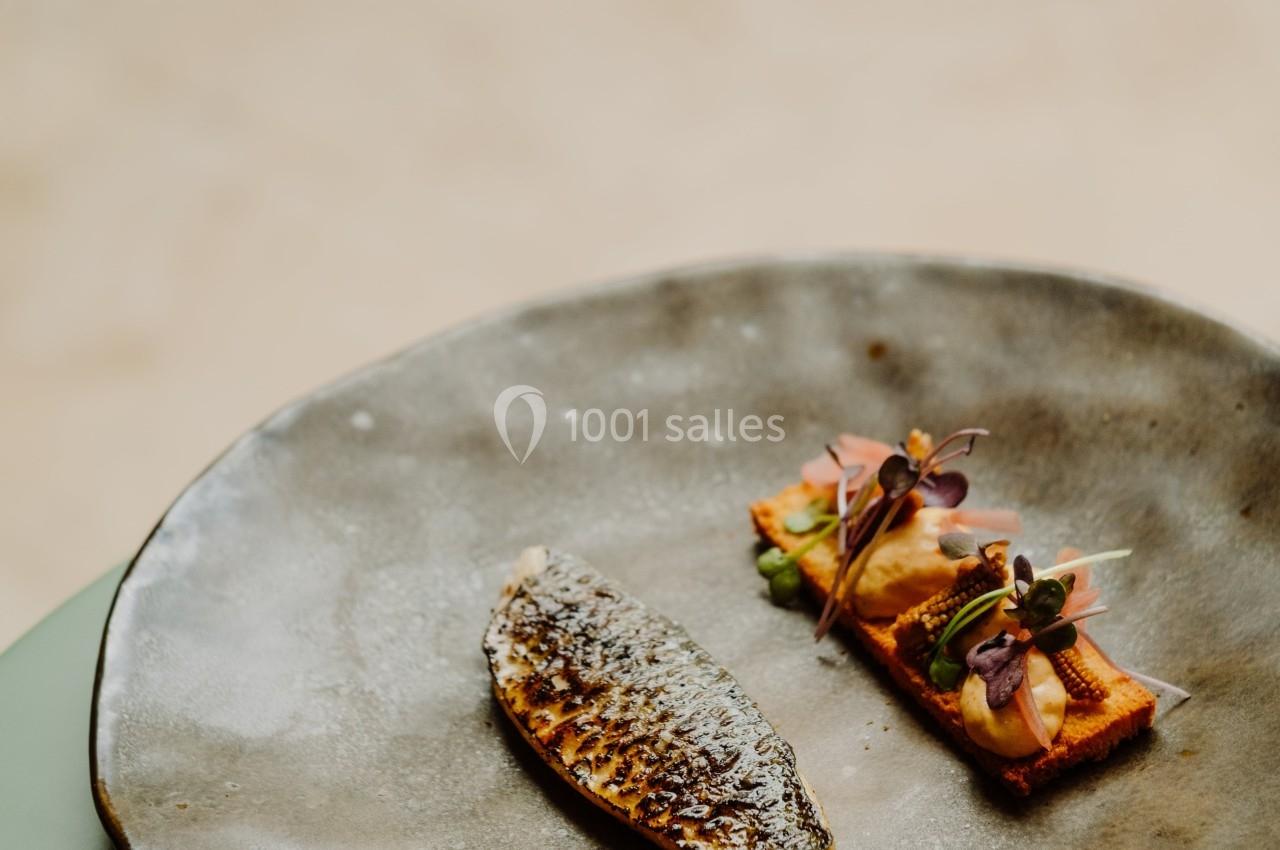 Filet de poisson grillé accompagné de légumes colorés et décoratifs, présenté sur une assiette en céramique.