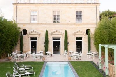 Fauteuil beige placé près d'un mur vert, avec un tableau encadré et des rideaux beiges en arrière-plan.