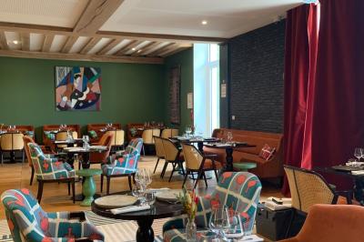 Fauteuil beige placé près d'un mur vert, avec un tableau encadré et des rideaux beiges en arrière-plan.