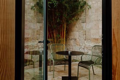 Fauteuil beige placé près d'un mur vert, avec un tableau encadré et des rideaux beiges en arrière-plan.