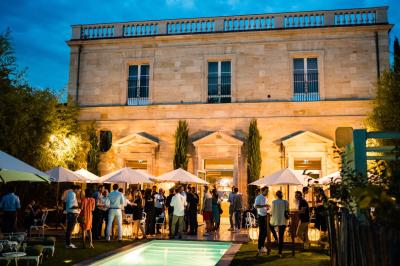 Fauteuil beige placé près d'un mur vert, avec un tableau encadré et des rideaux beiges en arrière-plan.