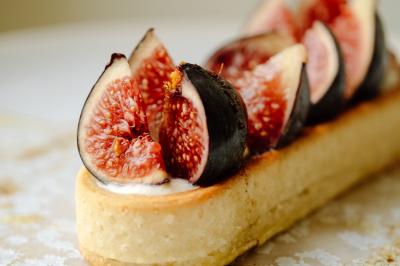 Fauteuil beige placé près d'un mur vert, avec un tableau encadré et des rideaux beiges en arrière-plan.