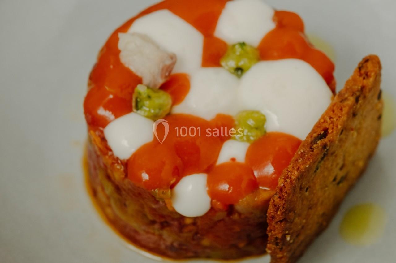 Tartare de légumes surmonté de sauces colorées, décoré de petits pois et accompagné d'un biscuit croustillant.