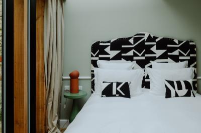 Miniature Location salle Le Bouscat (Gironde) - Maison Pavlov #15 Chambre d'hôtel avec lit double, tête de lit colorée, coin salon, lavabo éclairé et parquet en bois clair.