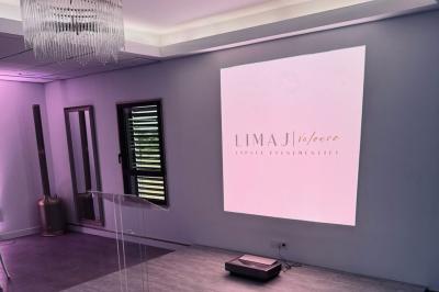 Des personnes assises assistent à une présentation dans une salle éclairée par des lumières violettes.