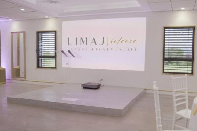 Des personnes assises assistent à une présentation dans une salle éclairée par des lumières violettes.