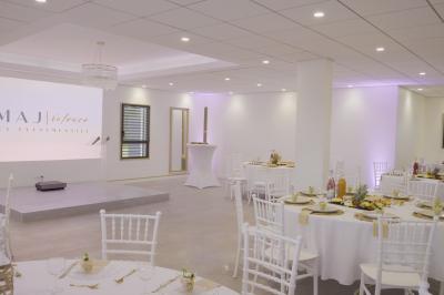 Des personnes assises assistent à une présentation dans une salle éclairée par des lumières violettes.