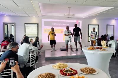 Des personnes assises assistent à une présentation dans une salle éclairée par des lumières violettes.