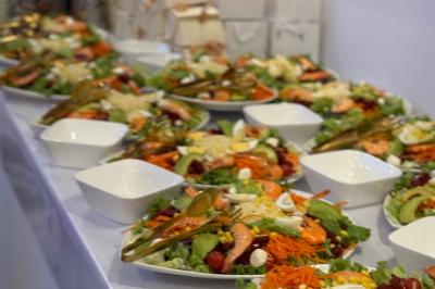 Un olivier taillé dans un grand bac blanc devant une façade moderne éclairée.
